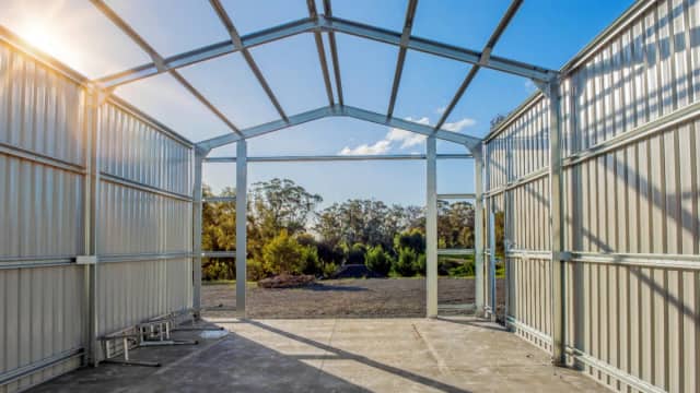 Metal building under construction with steel frame and concrete slab